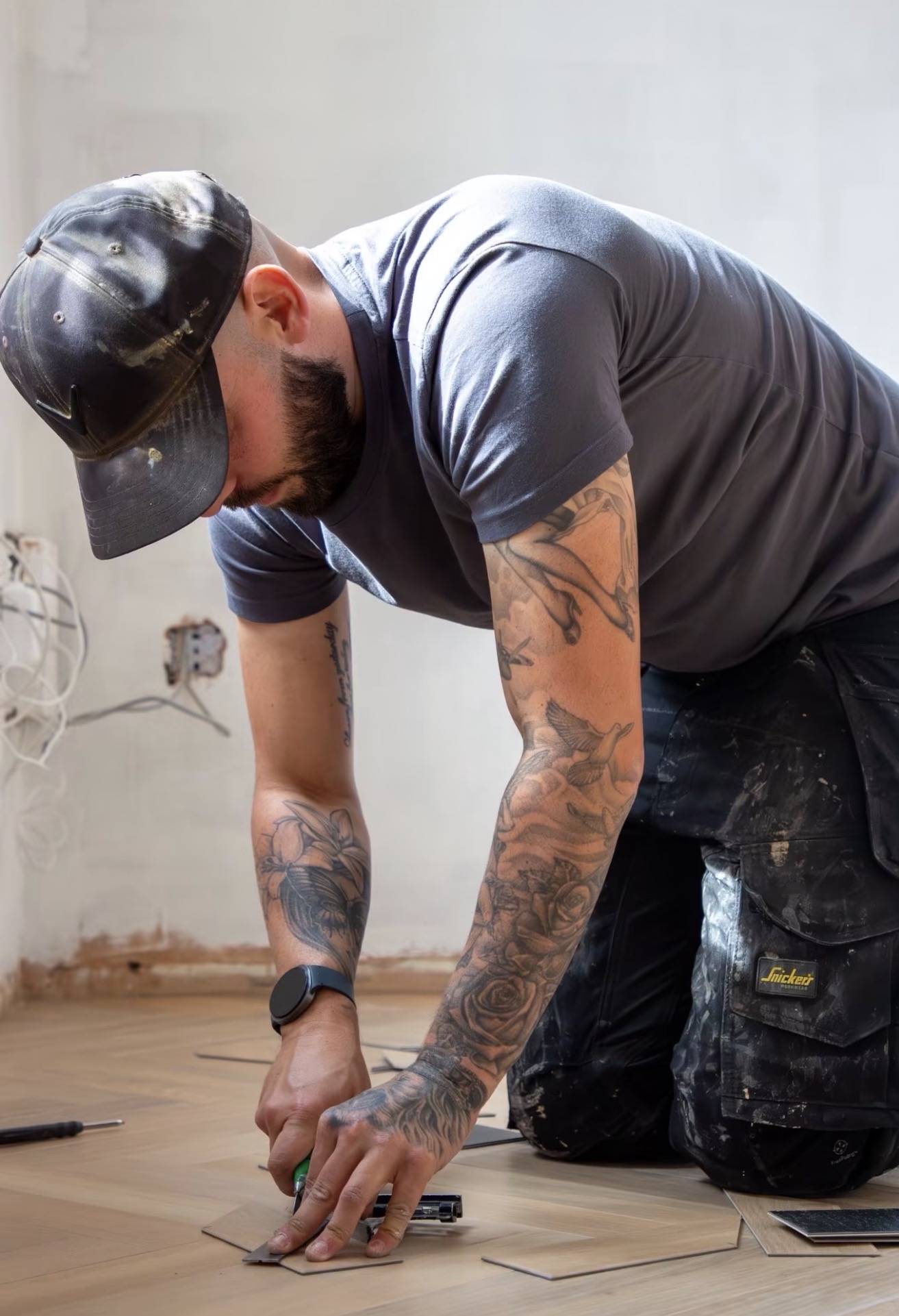 Sam kneeling on a herringbone floor, marking out a block
