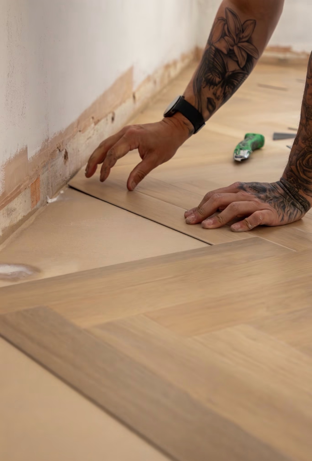 Hands setting a herringbone block against the wall line