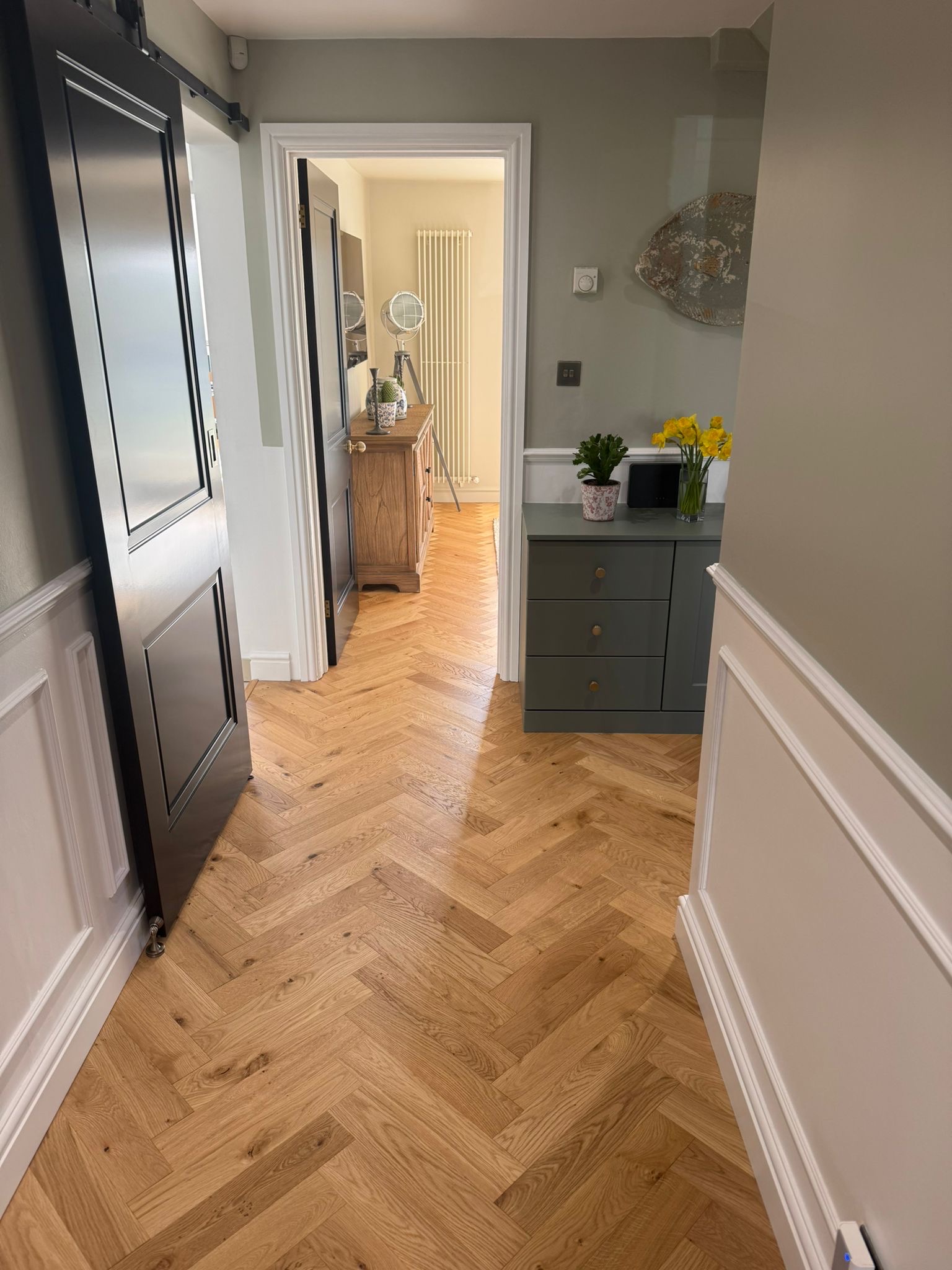 Herringbone hall with a black sliding door and sage panelling
