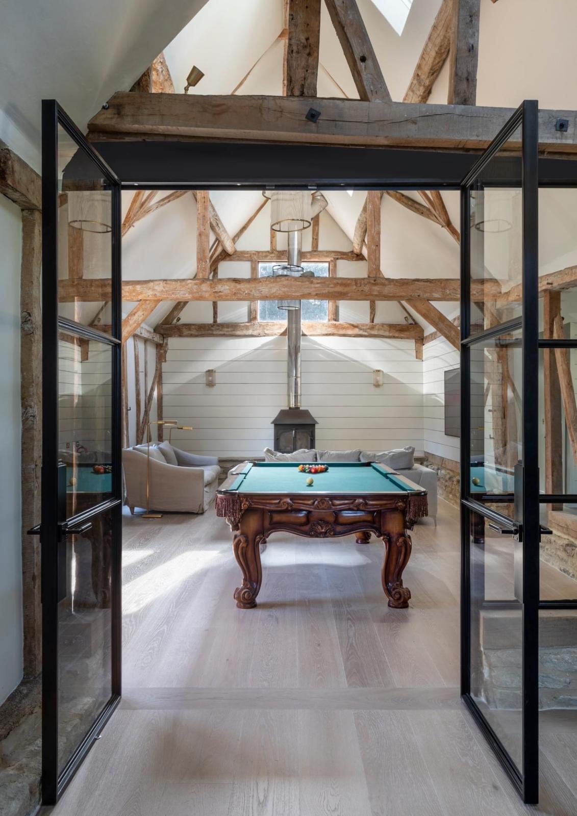 Oak floor seen through black steel doors in a timber-framed home
